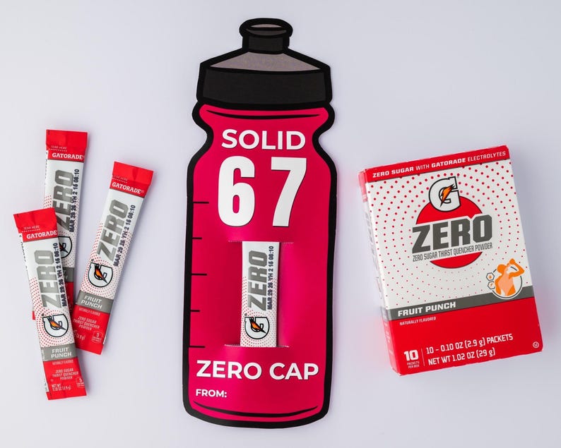 May include: A display of Gatorade Zero products. Includes a red and black bottle-shaped cutout with the text "SOLID 67" and "ZERO CAP", packets, and a box of Fruit Punch flavour. The box contains 10 packets, each 2.9g.
