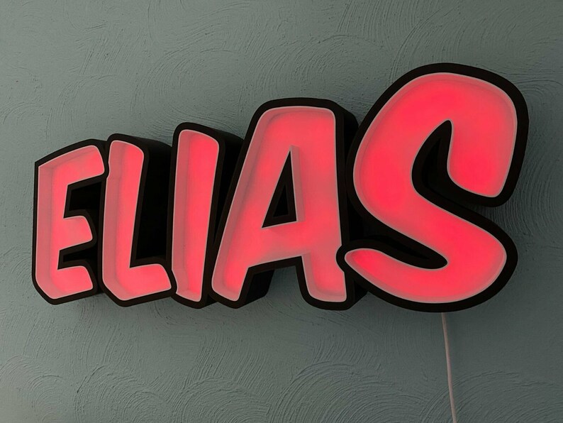 May include: A black and red neon sign with the name "ELIAS" in a bold, cartoon-style font.