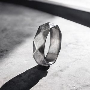 Puede incluir: Un anillo geométrico de plata con acabado texturizado.