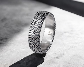 May include: A silver ring with a textured design of clouds. The ring is marked with the number "925" on the inside.