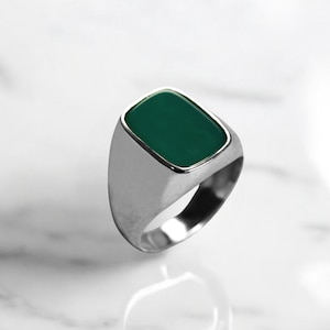 Puede incluir: Un anillo de plata con una piedra cuadrada de color verde oscuro.