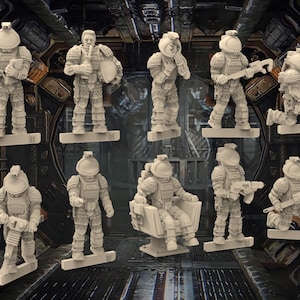 May include: A set of nine grey plastic figurines of space crew members wearing helmets and carrying tools. The figurines are posed in various action poses, including standing, sitting, and kneeling.
