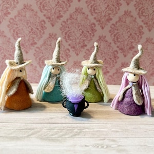 May include: Four felted figures wearing pointed hats and capes, each with long yarn hair in blonde, light blue, light green, and pink. They stand around a small black cauldron with a purple interior and white wispy material emerging from the top.