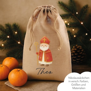 Puede incluir: Una bolsa de regalo de yute beige con cordón y una ilustración de dibujos animados de Papá Noel en rojo y blanco, sosteniendo un bastón dorado. El nombre "Theo" está impreso debajo. Naranjas en primer plano.