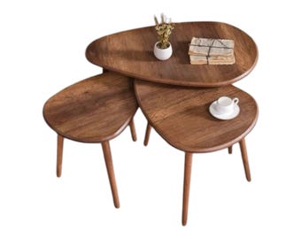 May include: A set of three nesting tables made of dark wood with a unique oval shape. The tables are arranged in a stack, with the largest table on the bottom and the smallest table on top. The tables have a simple, modern design and would be a great addition to any living room or office.