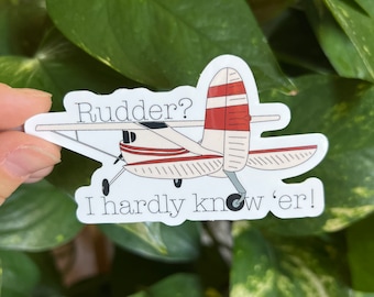May include: A white and red airplane sticker with the text "Rudder? I hardly know 'er!"