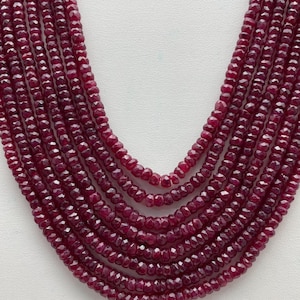 Può includere: Una collana multifilo composta da perle di rubino rosso sfaccettate. Le perle sono di un colore rosso profondo e ricco e hanno una forma leggermente irregolare.