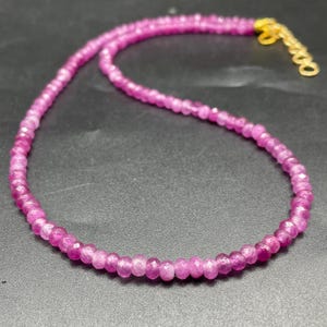 Puede incluir: Un delicado collar compuesto por pequeñas piedras preciosas rosas facetadas. El collar presenta un cierre y una cadena dorados. Las piedras preciosas son de un vibrante tono rosa, creando una hermosa y llamativa pieza de joyería.