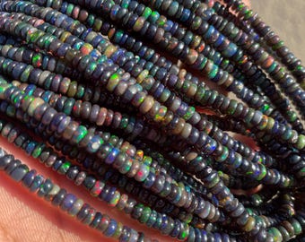 May include: A strand of dark iridescent opal beads. The beads are small and round, and they have a variety of colors, including black, green, blue, and purple.