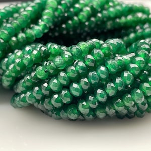 Peut inclure: Un brin de perles de pierres précieuses facettées vert foncé. Les perles sont rondes et ont une finition lisse et polie.