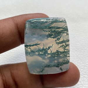 May include: A rectangular moss agate gemstone with a smooth, polished surface. The stone features a translucent, milky white base with intricate, branching dark green inclusions that resemble delicate forest foliage or mossy patterns.