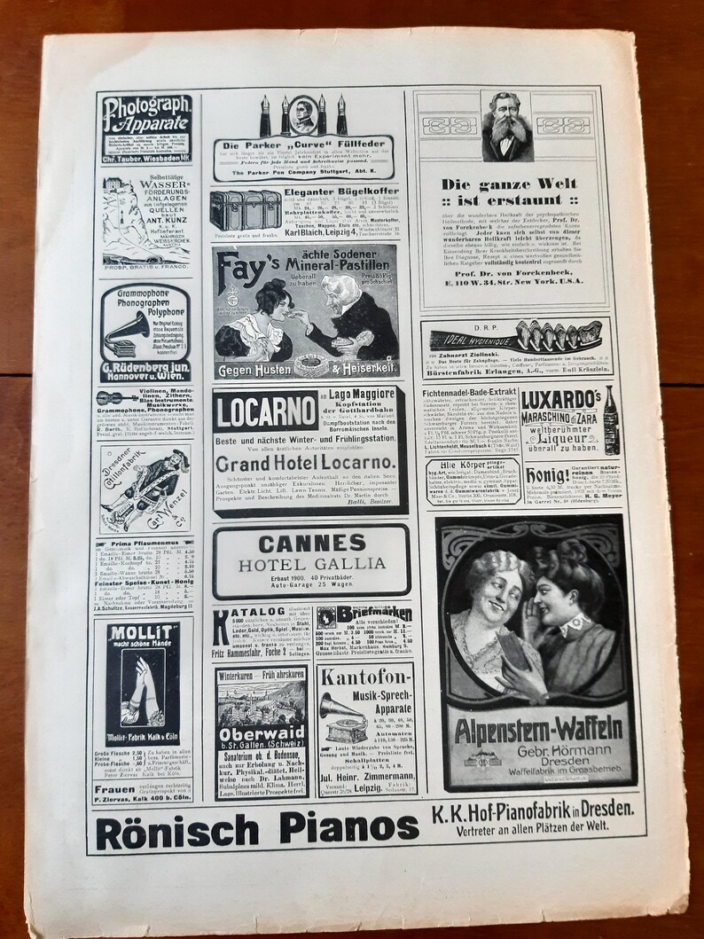 May include: A vintage magazine advertisement featuring various products, including a fountain pen, a suitcase, a mineral tablet, a phonograph, a hotel, a piano, a waffle iron, and a bottle of liqueur. The magazine ad is printed in black and white.