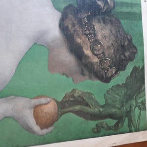 May include: A woman with dark hair and a crown of coins holds a brown fruit in her hand. She is lying on a green background with a leafy vine.