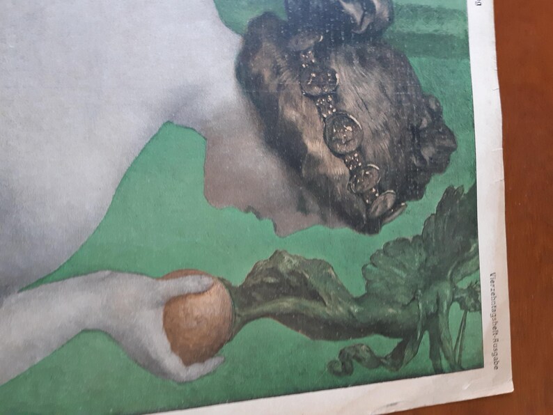 May include: A woman with dark hair and a crown of coins holds a brown fruit in her hand. She is lying on a green background with a leafy vine.