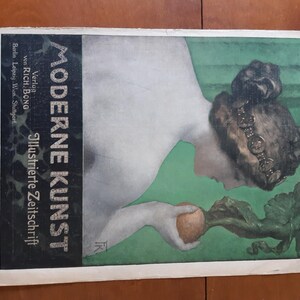 May include: A vintage magazine cover featuring a woman with a dark brown hat and a white dress. The magazine is titled "Moderne Kunst" and is an illustrated journal. The woman is holding a turnip in her hand.