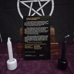 May include: A book cover with a black background and a white pentagram. The book title is "Tales of the Tortured, of the Possessed". The book cover features an excerpt from the book and a list of authors.