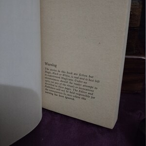 May include: A close-up of a book page with the text "Warning" in bold, followed by a paragraph explaining that the stories in the book are fiction, but magic is real and should be left to experienced magicians. The reader is advised not to attempt any of the rituals or invocations described in the book, and the editor and publishers are not responsible for any consequences that may result from ignoring this warning.