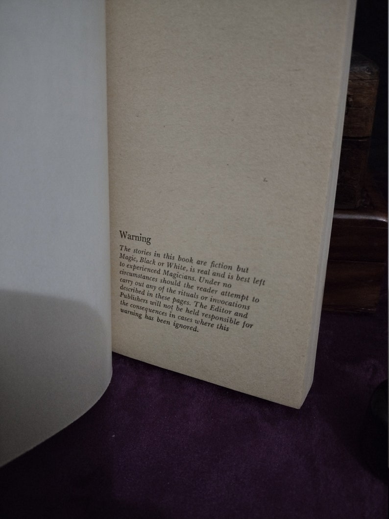 May include: A close-up of a book page with the text "Warning" in bold, followed by a paragraph explaining that the stories in the book are fiction, but magic is real and should be left to experienced magicians. The reader is advised not to attempt any of the rituals or invocations described in the book, and the editor and publishers are not responsible for any consequences that may result from ignoring this warning.