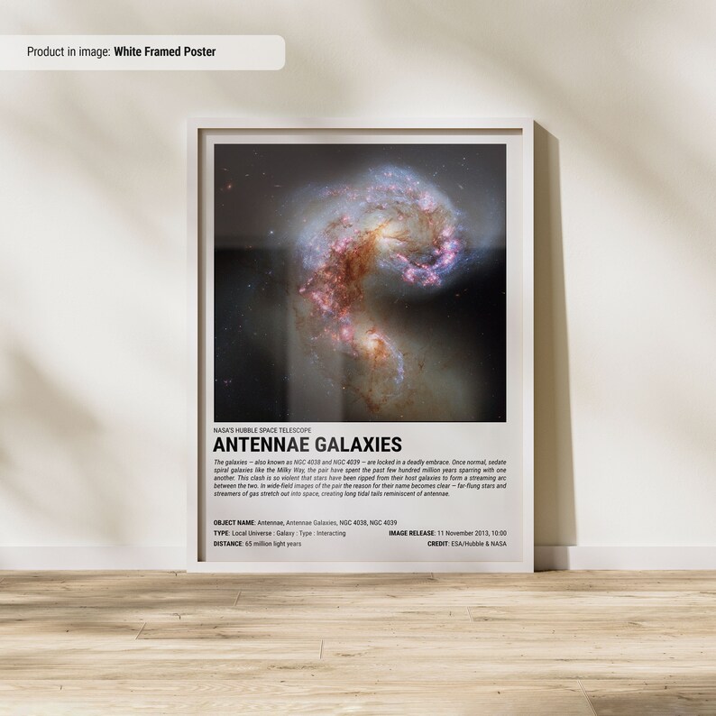 May include: White framed poster featuring a vibrant image of the Antennae Galaxies, a pair of interacting galaxies. The image shows swirling patterns of stars and gas, with text that reads "ANTENNAE GALAXIES". The poster is a striking piece of space art.