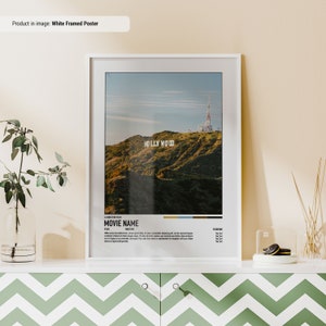 May include: White framed poster with a photo of the Hollywood sign on a hill with a radio tower in the background. The poster has a movie title card with the text "A DIRECTOR FILM MOVIE NAME" and "STARRING".
