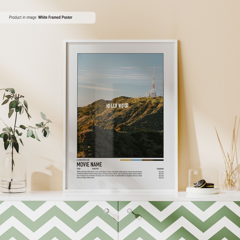 May include: White framed poster with a photo of the Hollywood sign on a hill with a radio tower in the background. The poster has a movie title card with the text "A DIRECTOR FILM MOVIE NAME" and "STARRING".