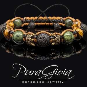 Peut inclure: Un bracelet en perles brun, noir et vert avec des accents dorés. Le bracelet est composé de perles de lave, d'œil de tigre et de jade vert. Les accents dorés sont de petites couronnes.