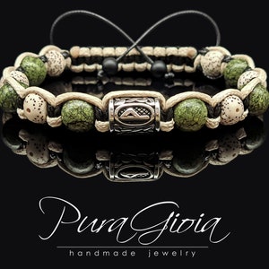 May include: A green and white beaded bracelet with a silver charm featuring a triangle symbol. The bracelet is made with a black cord and has a knot closure. The charm has the text "Pura Gioia" on it.