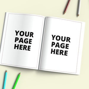 May include: A white open notebook with the text "YOUR PAGE HERE" on each page. There are colored pencils on a light yellow surface.