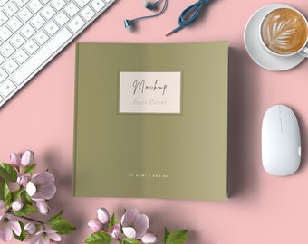 以下が含まれることがあります： ピンクの背景に、白いキーボード、白いマウス、コーヒーカップ、ピンクの花が置かれた、緑色の本の表紙のモックアップ。表紙には「Mockup Book Cover」と「BY RAMIS DESIGN」の文字が書かれている。