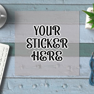 Puede incluir: Una pegatina cuadrada blanca con texto negro que dice "YOUR STICKER HERE" sobre un fondo gris claro. La pegatina está sobre una superficie de madera azul claro.