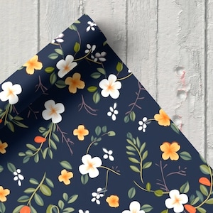 May include: A sheet of blue wrapping paper with a white and yellow floral pattern. The paper is rolled up and the edge is visible.