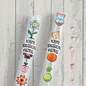 May include: Two clear plastic tubes with colorful stickers on them. The stickers include a flower, a pot, a smiley face, a llama, a green ball, and a cartoon character. The text "YOUR DESIGN HERE" is on each tube.