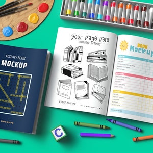 Pode incluir: Uma vista de cima de um livro de atividades azul com um caça-palavras na capa, um livro de atividades branco com uma página para colorir de livros, um conjunto de marcadores coloridos, um conjunto de lápis de cor, um conjunto de giz de cera, uma paleta de pintura e tubos de tinta. Os livros de atividades são intitulados "Activity Book Mockup" e "Book Mockup".