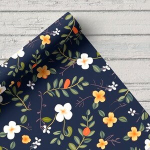 May include: A roll of blue wrapping paper with a floral pattern featuring white and yellow flowers, green leaves, and orange berries.