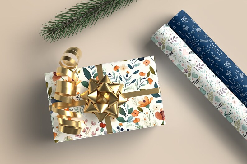 May include: A gift wrapped in white floral patterned paper with a gold ribbon and bow. Two rolls of wrapping paper are visible in the background, one with a blue floral pattern and the other with a blue pattern of scientific symbols.