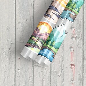 May include: Roll of clear vinyl sticker paper with colourful mountain landscape designs. The stickers feature a variety of scenes, including a mountain range with a sun setting behind it, a mountain lake with a snowy peak in the background, and a forest scene with a river running through it.