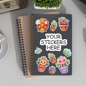 May include: A black spiral bound notebook with a brown cover. The notebook has a variety of colorful stickers on the front, including flowers, plants, and boats. The text "YOUR STICKERS HERE" is written in white on the notebook.
