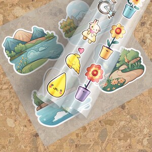 May include: A sheet of clear sticker paper with various colourful cartoon stickers. The stickers include a mountain scene, a flower in a pot, a bird, a raindrop, a bunny in a dress, and a bicycle.