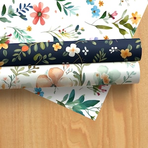 May include: Three rolls of floral patterned wrapping paper. The top roll is white with a blue floral pattern, the middle roll is white with a peach floral pattern, and the bottom roll is white with a green floral pattern.