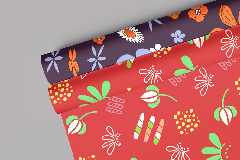 May include: Two rolls of red and purple wrapping paper with floral patterns. The red paper has white flowers, green leaves, and yellow dots. The purple paper has white flowers, orange flowers, and blue flowers.
