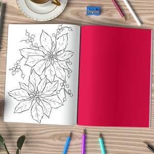 May include: An open coloring book with a black and white illustration of poinsettia flowers. The book is on a wooden table with pencils, erasers, and a cup of coffee.