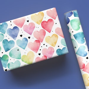 以下が含まれることがあります： カラフルな水彩のハートと黒いドットが繰り返し描かれた白い包装紙のロール