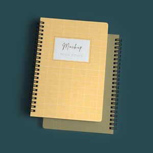 Può includere: Due quaderni a spirale, uno con una copertina gialla e un motivo a griglia, l'altro con una copertina verde. Il quaderno giallo ha un'etichetta bianca con il testo "Mockup Book Cover".