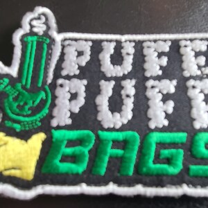May include: Green and white embroidered patch with a cartoon bong and the text "PUFF PUFF BAGS" in white.