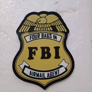 May include: A yellow and black patch with an eagle design and the text "Four Bags In FBI Airmail Agent".