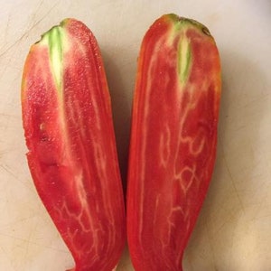 May include: Two halves of a red tomato with green veins, showing the inside of the fruit.