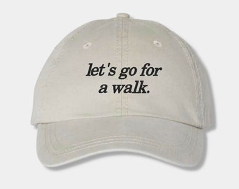May include: A beige baseball cap with the text "let's go for a walk." embroidered in black.