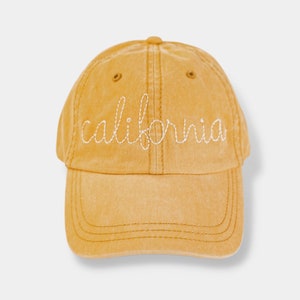 May include: A yellow baseball cap with the word "california" embroidered in white on the front.