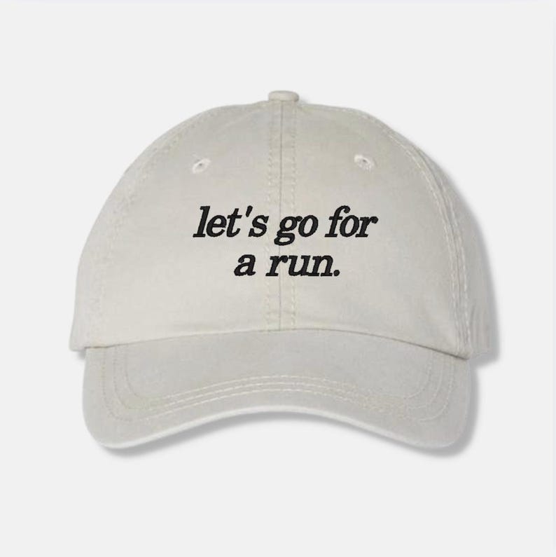 May include: A beige baseball cap with the text "let's go for a run." embroidered in black.