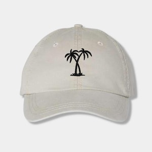 May include: A beige baseball cap with a black silhouette of two palm trees on the front.